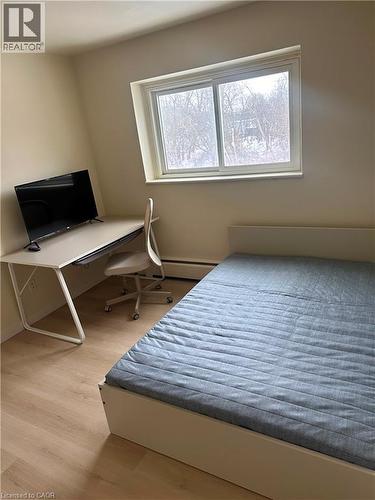 Bright room featuring a window with a tree-lined backdrop, light wood-finish flooring, a baseboard heater, and neutral wall paint - 145 Macgregor Crescent Unit# 8 (R1), Waterloo, ON - Indoor Photo Showing Bedroom