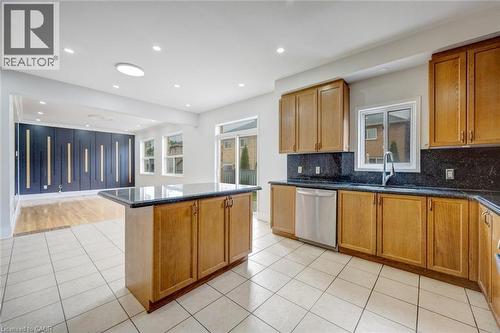 Kitchen featuring wood cabinetry, dark stone countertops, stainless steel dishwasher, and a center island - 5 Freshspring Drive, Brampton, ON - Indoor Photo Showing Kitchen