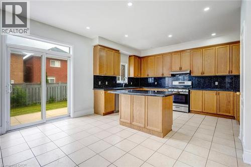 Spacious kitchen featuring light wood cabinetry, dark countertops, tile flooring, recessed lighting, and a sliding glass door to the backyard - 5 Freshspring Drive, Brampton, ON - Indoor Photo Showing Kitchen