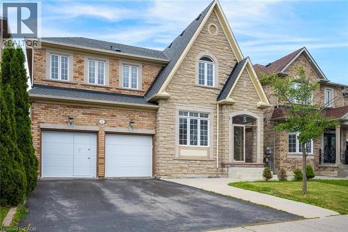 Exterior featuring a stone and brick facade, an arched entryway, multiple gabled rooflines, a two-car garage, and a paved driveway - 5 Freshspring Drive, Brampton, ON - Outdoor With Facade