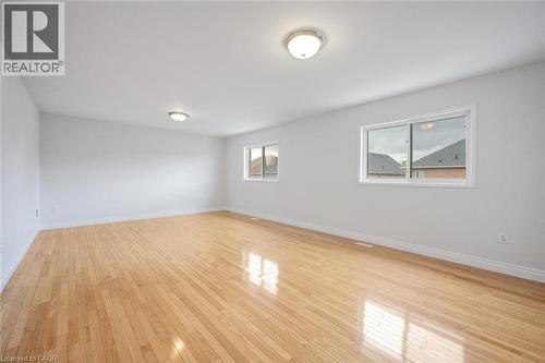 Spacious room featuring wood-finish flooring, two windows with white frames, and two ceiling-mounted dome light fixtures - 5 Freshspring Drive, Brampton, ON - Indoor Photo Showing Other Room