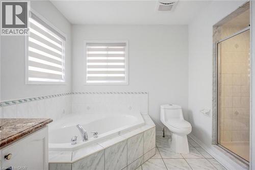 Corner soaking tub with tiled surround, dual windows with blinds, walk-in shower with glass enclosure, toilet, and a vanity with a granite-finish countertop - 5 Freshspring Drive, Brampton, ON - Indoor Photo Showing Bathroom