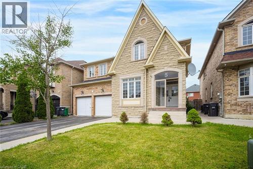 Stone facade residence featuring an arched portico entry with double glass doors, a prominent gable roofline, multiple white-framed windows, and a two-car garage with individual doors - 5 Freshspring Drive, Brampton, ON - Outdoor With Facade