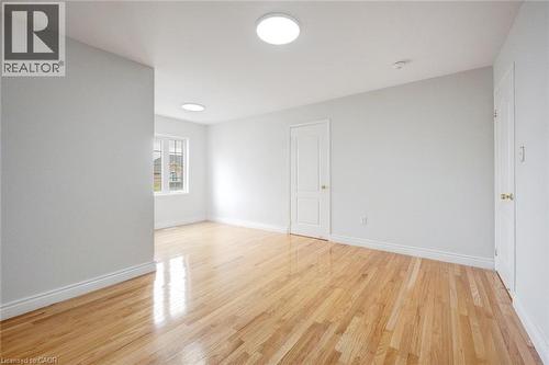 Spacious room featuring wood-finish flooring, white walls, multiple light fixtures, and a grid-paned window - 5 Freshspring Drive, Brampton, ON - Indoor Photo Showing Other Room