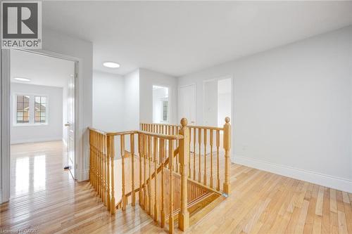 Hardwood flooring throughout a bright upper-level hallway featuring a wooden staircase and balusters, multiple doorways, and recessed lighting - 5 Freshspring Drive, Brampton, ON - Indoor Photo Showing Other Room