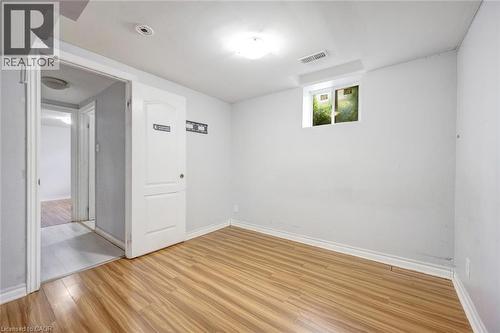 Room featuring wood-finish flooring, white baseboards, a white interior door, a light fixture, and a window - 5 Freshspring Drive, Brampton, ON - Indoor Photo Showing Other Room