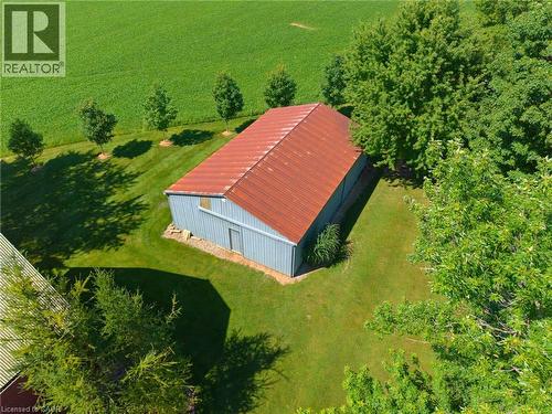 Metal barn with a corrugated red roof, light blue siding, and a single entry door - 8430 Road 146, Listowel, ON - Outdoor