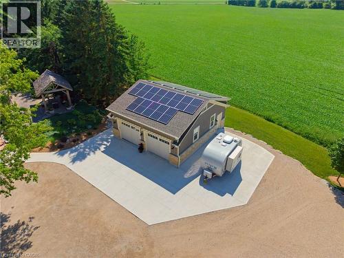 Detached multi-car garage featuring solar panels, dual garage doors, and stone and siding exterior - 8430 Road 146, Listowel, ON - Outdoor