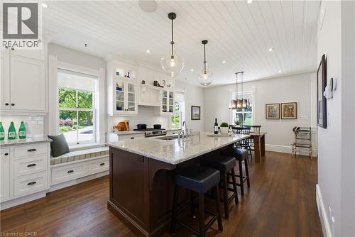 Spacious kitchen featuring an expansive center island with seating, granite countertops, wood-finish flooring, and a window seat with integrated storage - 8430 Road 146, Listowel, ON - Indoor Photo Showing Kitchen With Double Sink With Upgraded Kitchen