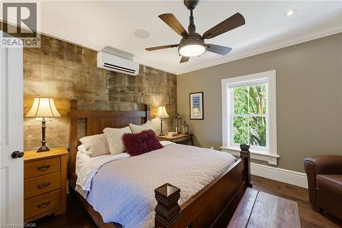 Bedroom featuring a decorative wood-panel accent wall, crown molding, a ceiling fan with integrated lighting, and a wall-mounted air conditioning unit - 8430 Road 146, Listowel, ON - Indoor Photo Showing Bedroom