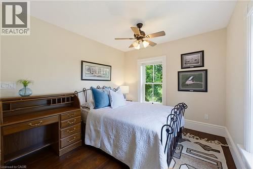 Bedroom featuring rich wood-finish flooring, a ceiling fan with integrated lighting, a double-hung window, and neutral wall tones - 8430 Road 146, Listowel, ON - Indoor Photo Showing Bedroom