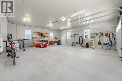 Spacious garage featuring a concrete floor, multiple windows, a rear access door, track lighting, and overhead garage door rails - 8430 Road 146, Listowel, ON - Indoor Photo Showing Garage