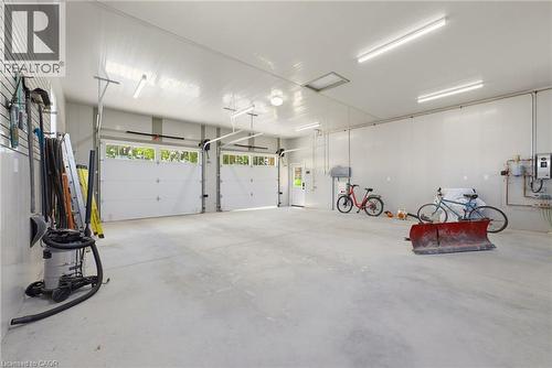 Spacious two-bay garage featuring bright overhead lighting, a utility door, and a built-in wall organization system - 8430 Road 146, Listowel, ON - Indoor Photo Showing Garage