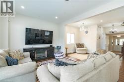 Spacious living area featuring wood-finish flooring, recessed lighting, and a decorative fireplace unit - 