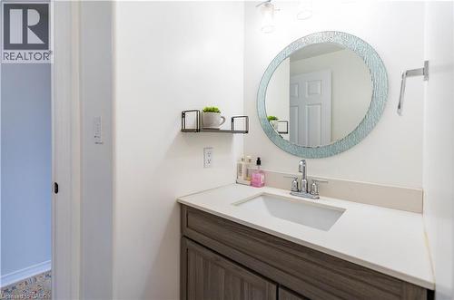 Bathroom vanity with a white rectangular undermount sink, light-colored countertop, and a wood-finish cabinet - 122 Iron Gate Street, Kitchener, ON - Indoor Photo Showing Bathroom