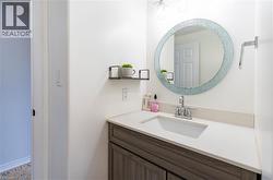 Bathroom vanity with a white rectangular undermount sink, light-colored countertop, and a wood-finish cabinet - 