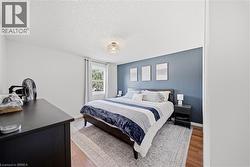 Bedroom featuring hardwood flooring, a window with natural light, a textured ceiling, and a contemporary ceiling light fixture - 