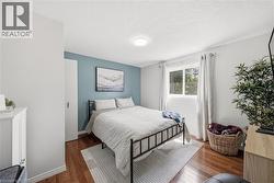 Interior space featuring wood-finish flooring, a contemporary ceiling light fixture, a window with natural light, and a built-in closet with a white door - 
