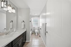 Full bathroom featuring a single vanity with dark cabinetry and a white countertop, chrome fixtures, tile flooring, and a frosted window - 