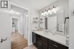 Bathroom vanity featuring a white countertop with integrated sink, dark wood-finish cabinetry, and a large wall-mounted mirror - 