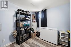 Room featuring wood-finish flooring, light blue walls, and a window with dark curtains - 