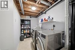 Dedicated laundry area featuring tile flooring, exposed ceiling joists, and a wall-mounted storage shelf - 