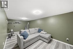 Spacious room featuring muted green walls and light wood-finish flooring - 