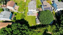 Expansive rear yard featuring a large manicured lawn, established shade tree, and detached shed - 