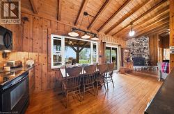 Open-concept living space with exposed wood-beam vaulted ceilings and wood-panel walls - 