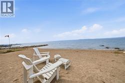 Sandy beach shoreline featuring Adirondack chairs and a calm body of water - 
