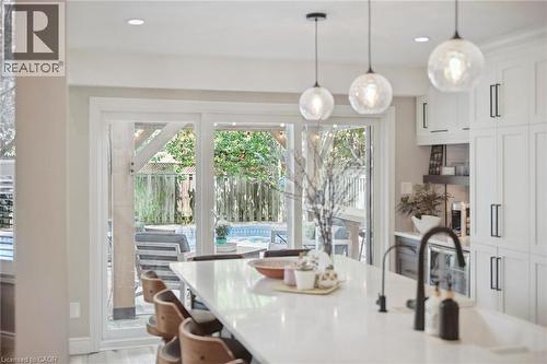 Modern kitchen featuring a large island with seating, white cabinetry, dark hardware, and pendant lighting - 916 Rush Meadow Court, Kitchener, ON - Indoor