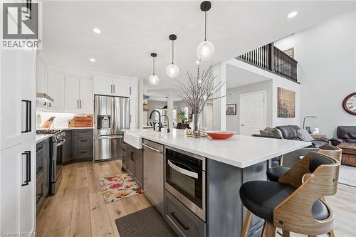 Modern kitchen featuring an expansive center island with integrated microwave and farm sink - 916 Rush Meadow Court, Kitchener, ON - Indoor Photo Showing Kitchen With Upgraded Kitchen