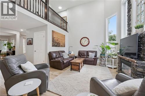 Two-story living area featuring wood-finish flooring, a stone-clad fireplace, and an open balcony overlooking the space - 916 Rush Meadow Court, Kitchener, ON - Indoor Photo Showing Living Room With Fireplace