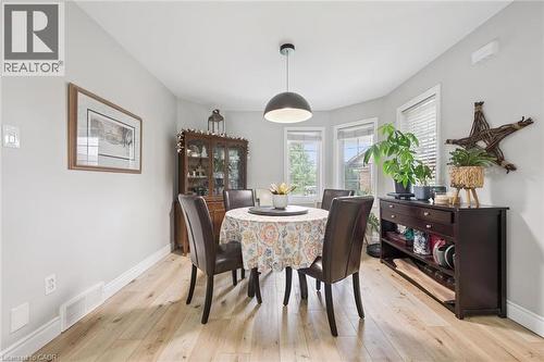 Dining area featuring wood-finish flooring, light gray walls, white baseboards, and a contemporary pendant light fixture - 916 Rush Meadow Court, Kitchener, ON - Indoor Photo Showing Dining Room