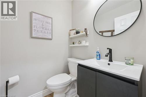 Contemporary powder room featuring a single-sink vanity with dark cabinetry, matte black faucet, and an oval mirror - 916 Rush Meadow Court, Kitchener, ON - Indoor Photo Showing Bathroom