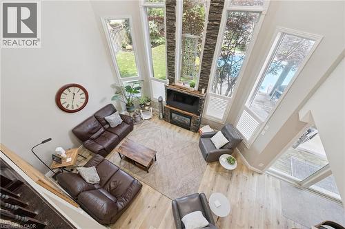 Two-story great room featuring a stone-faced fireplace with a wood mantel, high ceilings, and extensive window walls - 916 Rush Meadow Court, Kitchener, ON - Indoor Photo Showing Other Room