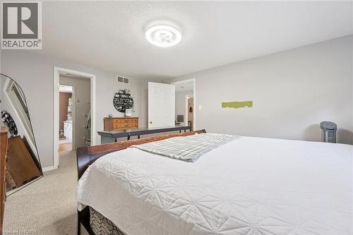 Carpeted room featuring light gray walls, a flush-mount ceiling light fixture, and an open doorway to an additional interior space - 916 Rush Meadow Court, Kitchener, ON - Indoor Photo Showing Bedroom