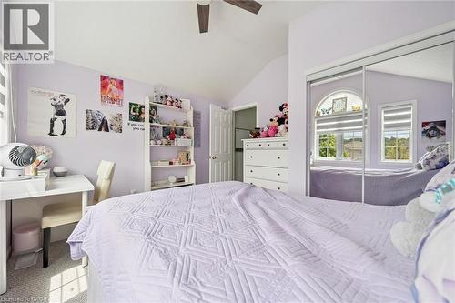 Sloped ceiling bedroom featuring a ceiling fan, carpet flooring, a built-in closet with mirrored doors, and two windows - 916 Rush Meadow Court, Kitchener, ON - Indoor Photo Showing Bedroom
