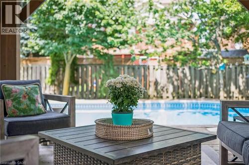 Covered outdoor patio with wood-finish structural beams, featuring a rectangular inground pool with concrete surround, and perimeter fencing - 916 Rush Meadow Court, Kitchener, ON - Outdoor With In Ground Pool With Deck Patio Veranda