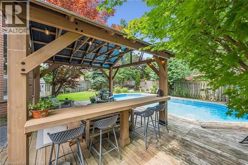 Outdoor entertainment area featuring a wooden gazebo with a corrugated roof, a built-in bar, and a swimming pool - 916 Rush Meadow Court, Kitchener, ON - Outdoor With In Ground Pool