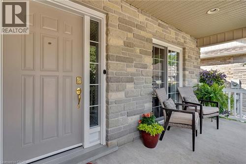 Front entrance featuring a paneled door with sidelight, stone facade, covered porch, and a sliding glass door - 350 Doon Valley Drive Unit# 6D, Kitchener, ON - Outdoor With Deck Patio Veranda With Exterior