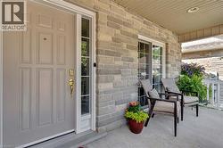 Front entrance featuring a paneled door with sidelight, stone facade, covered porch, and a sliding glass door - 