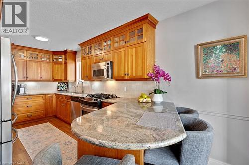 Kitchen featuring natural wood cabinetry, stainless steel appliances, light granite countertops, and recessed lighting - 350 Doon Valley Drive Unit# 6D, Kitchener, ON - Indoor Photo Showing Kitchen