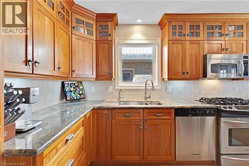 Kitchen featuring wood cabinetry, stainless steel appliances, a stainless steel double basin sink, and a tile backsplash - 350 Doon Valley Drive Unit# 6D, Kitchener, ON - Indoor Photo Showing Kitchen With Double Sink