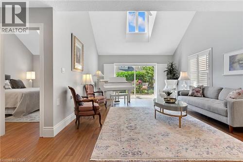 Vaulted ceilings featuring a skylight, wood-finish flooring, and sliding glass doors opening to a lush outdoor space - 350 Doon Valley Drive Unit# 6D, Kitchener, ON - Indoor Photo Showing Living Room