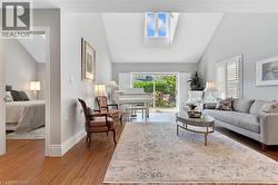Vaulted ceilings featuring a skylight, wood-finish flooring, and sliding glass doors opening to a lush outdoor space - 