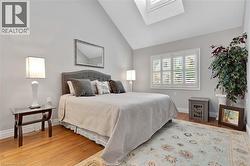 Room featuring vaulted ceilings, wood-finish flooring, and a skylight - 