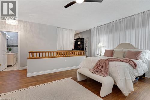 Spacious bedroom featuring wood-finish flooring, a contemporary ceiling fan, and extensive sheer drapery - 350 Doon Valley Drive Unit# 6D, Kitchener, ON - Indoor Photo Showing Bedroom