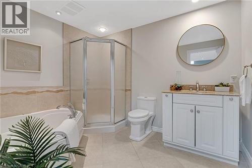 Bathroom featuring a built-in tub, corner shower with frosted glass, and a single vanity with a stone countertop - 350 Doon Valley Drive Unit# 6D, Kitchener, ON - Indoor Photo Showing Bathroom