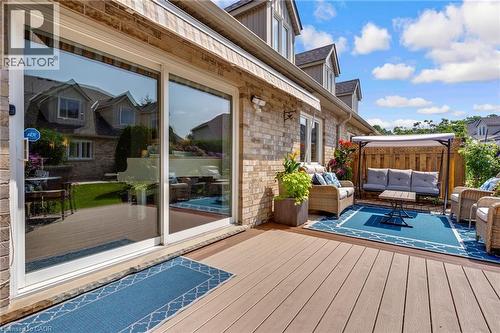 Expansive outdoor deck featuring wood-finish decking, brick exterior, and white-framed sliding glass doors - 350 Doon Valley Drive Unit# 6D, Kitchener, ON - Outdoor With Deck Patio Veranda